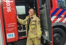 Brandweervrijwilliger Eline bij de deur van een brandweerwagen