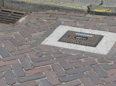 Een gele pijl op de straat wijst naar een putdeksel