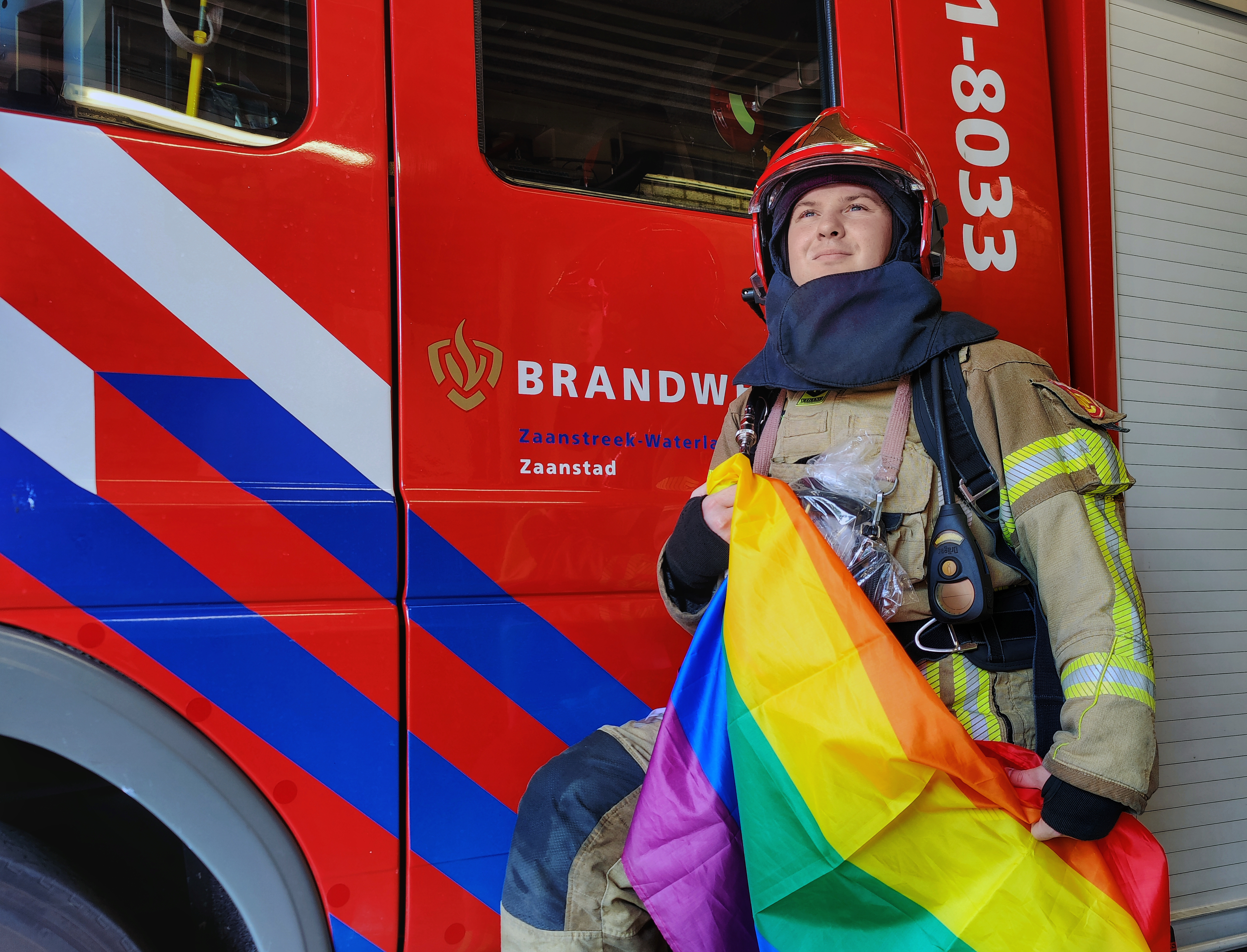 Tom van Lingen in brandweerpak met de pride vlag